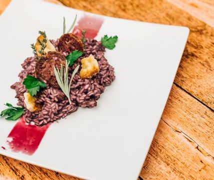 Risotto con erbe servita su piatto biancho, impiattamento elegante e moderno.