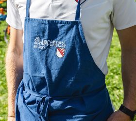 Un uomo che porta un costume tradizionale tiene in mano un calice di vino bianco e uno spuntino