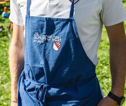 Un uomo che porta un costume tradizionale tiene in mano un calice di vino bianco e uno spuntino