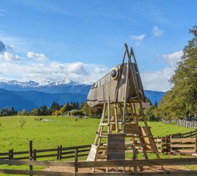 Grande struttura da gioco in legno a forma di testa di cavallo su un prato con panorama montano.