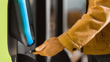 Passeggero convalida il biglietto con lo smartphone al lettore verde alla porta dell’autobus.