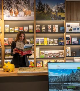 Una donna legge un opuscolo davanti a uno scaffale informativo nell'ufficio turistico