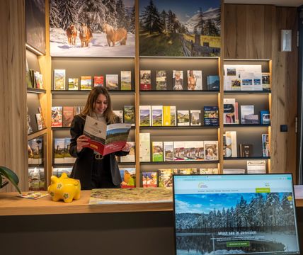 Una donna legge un opuscolo davanti a uno scaffale informativo nell'ufficio turistico
