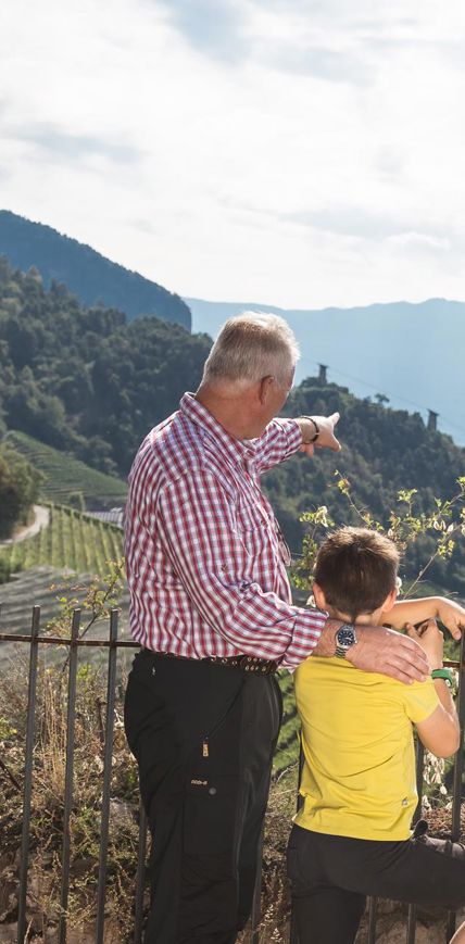 Nonno indica al nipote la vista panoramica sulla città di Bolzano e le montagne.